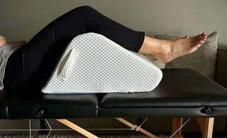 woman resting on massage table using ergonomic leg pillow for balanced sleep positioning