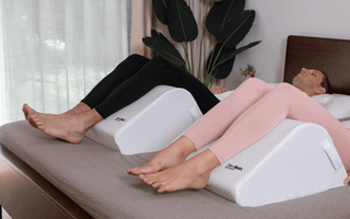 a couple recovering at home in bed using ergonomic leg wedge for balanced elevation comfort