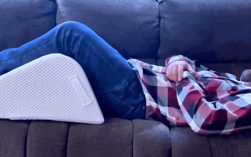 man in sofa using ergonomic leg wedge cushion with high-density firm foam design