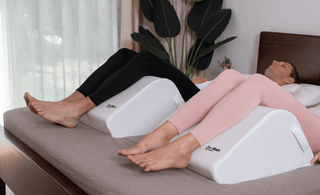 a couple recovering at home in bed using ergonomic leg wedge for balanced elevation comfort