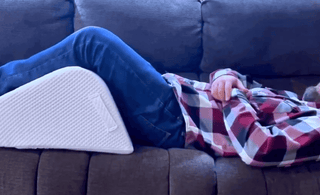 man in sofa using ergonomic leg wedge cushion with high-density firm foam design