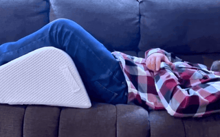 man in sofa using ergonomic leg wedge cushion with high-density firm foam design