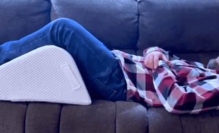 man in sofa using ergonomic leg wedge cushion with high-density firm foam design