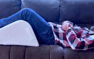 man in sofa using ergonomic leg wedge cushion with high-density firm foam design